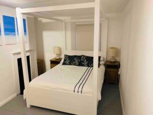 ein Schlafzimmer mit einem weißen Himmelbett mit zwei Lampen in der Unterkunft Cosy private cottage near beach in Ilfracombe