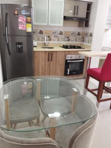 a kitchen with a glass table and two chairs and a refrigerator at apartamento cerca al aeropuerto parqueadero privado conjunto cerrado bilbao in Cúcuta