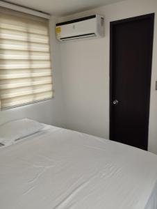 sypialnia z białym łóżkiem i oknem w obiekcie apartamento cerca al aeropuerto parqueadero privado conjunto cerrado bilbao w mieście Cúcuta