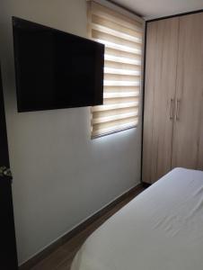 a bedroom with a bed and a flat screen tv at apartamento cerca al aeropuerto parqueadero privado conjunto cerrado bilbao in Cúcuta