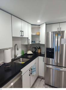 a kitchen with white cabinets and a stainless steel refrigerator at Cozy & Private Entire Basement in Winnipeg