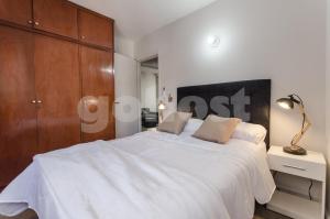 a bedroom with a large white bed with a wooden cabinet at Amazing Apartment Near La Costanera in Asuncion