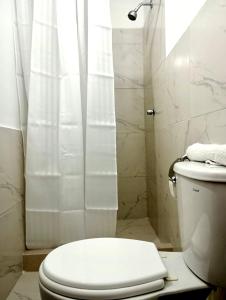 a white bathroom with a toilet and a shower at Piccolo Bed & Breakfast in Tarapoto