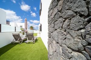 a stone wall and a patio with chairs and a table at Casa de los Belges in Yaiza