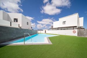 a house with a swimming pool in front of a building at Casa de los Belges in Yaiza