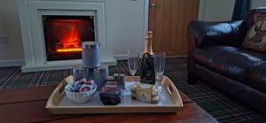 a tray of food and drinks on a table with a fireplace at Ben Vorlich Cottage in Tarbet