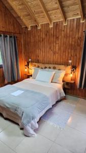 een slaapkamer met een groot bed en houten wanden bij Chalés Monte Verde in Bom Jardim da Serra