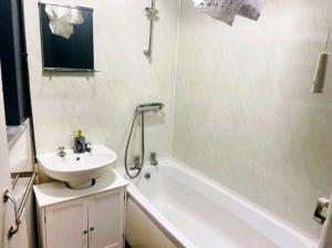 a bathroom with a sink and a white tub and a sink at King Charles House in Gillingham