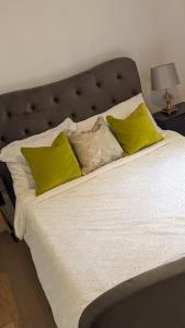 Una cama con almohadas amarillas encima. en Thurrock-Grays Cosy 2 bed Flat easy access to London, en Grays