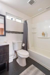 a white bathroom with a toilet and a bath tub at Blocks To The Beach Huge Private Fence Yard Home in Oceanside