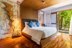 um quarto com uma cama grande e uma parede de pedra em Pousada Boutique Figueira da Serra em Campos do Jordão