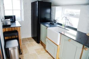cocina con fregadero y nevera negra en Lovely cottage with private garden, en Penryn