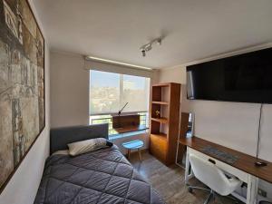 Schlafzimmer mit einem Bett, einem Schreibtisch und einem TV in der Unterkunft Departamento full equipo en Valparaiso in Viña del Mar