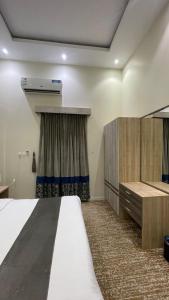 a bedroom with a bed and a dresser and a bed sidx sidx sidx sidx at شهرزاد للأجنحة الفندقية in Abū Qa‘ar