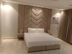 a bedroom with a large white bed and a wall at حكاية مسكن in Taif