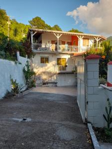 a white house with a fence and a driveway at Chez Lucile et Gilbert in Bouillante
