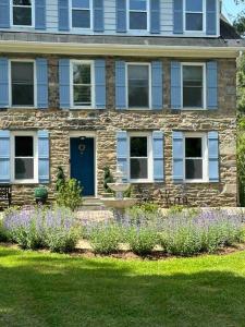 a stone house with a blue door and some flowers at Colonial Chic - 3BR home, VA wine country near Harpers Ferry in Purcellville