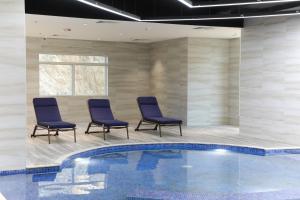a swimming pool with three chairs and a table and a pool at TIME Ruba Hotel & Suites in Makkah