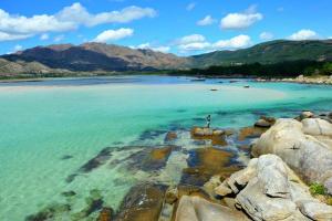 a person standing on some rocks in the water at Playa de Carnota Lofts in Pedrafigueira
