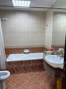 ein Badezimmer mit einer Badewanne, einem WC und einem Waschbecken in der Unterkunft Amazing Beachfront Holiday Home in Ajman 