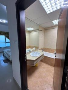 a bathroom with a sink and a tub and a mirror at Amazing Beachfront Holiday Home in Ajman 