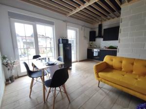 a living room with a yellow couch and a table at Playa de Carnota Lofts in Pedrafigueira