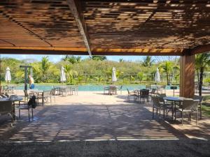a patio with tables and chairs next to a pool at Vila do Lago, Praia do Forte in Mata de Sao Joao