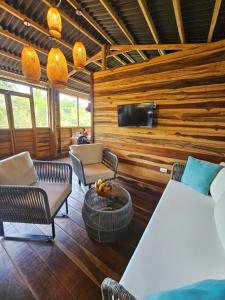 a room with a bed and chairs and a tv at La Casa Del Mono in Minca