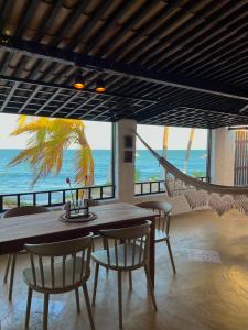 een eetkamer met een tafel en stoelen en de oceaan bij Casa Pé na Areia Maracajau in Maxaranguape