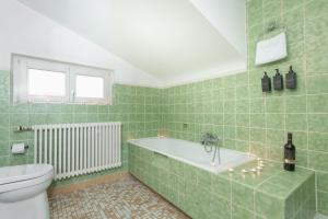 a green tiled bathroom with a tub and a toilet at Bodensee-Haus IStayUnixI Seenähe-Terrasse-Garten-Netflix-Parkplatz in Radolfzell am Bodensee