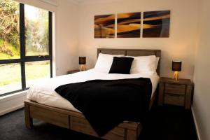 Un dormitorio con una cama grande y una ventana en Majestic 2 bedroom villa with panoramic bay views, en Strahan