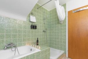 W wyłożonej zielonymi kafelkami łazience znajduje się wanna i umywalka. w obiekcie Bodensee-Haus IStayUnixI Seenähe-Terrasse-Garten-Netflix-Parkplatz w mieście Radolfzell am Bodensee