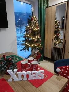 a christmas tree in a living room with mmas sign at Domek pod Szczyrkiem z ogrodem na wyłączność W CENIE GORĄCA BANIA in Szczyrk