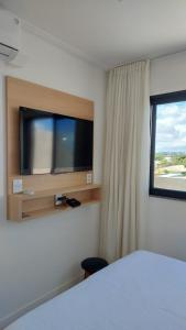 Schlafzimmer mit einem TV, einem Bett und einem Fenster in der Unterkunft Guarajuba, Camaçari, Bahia, 2 quartos com suíte, cobertura, terraço in Camassari