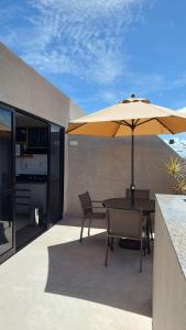 eine Terrasse mit Tisch und Sonnenschirm in der Unterkunft Guarajuba, Camaçari, Bahia, 2 quartos com suíte, cobertura, terraço in Camassari