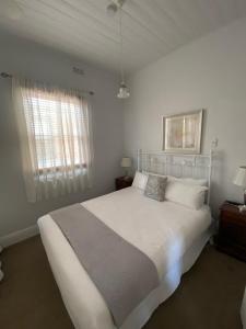 a white bedroom with a bed and a window at Seaview House in Queenscliff