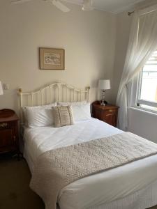 a bedroom with a bed with white sheets and a window at Seaview House in Queenscliff