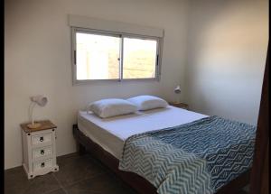 a bedroom with a bed and a window at Casa de Coral in Punta Del Diablo