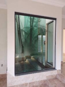 uma grande janela de vidro num quarto com uma planta em chácara Gato de Botas em Socorro
