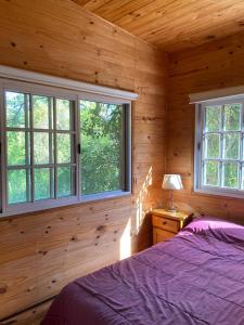 1 dormitorio con 1 cama y ventanas en una cabaña de madera en Hidden Island Hostel en Tigre
