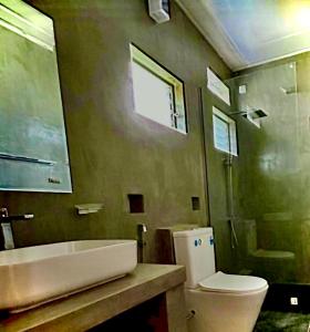 een badkamer met een toilet, een wastafel en een spiegel bij Oceanic Shades - Mount Lavinia in Mount Lavinia