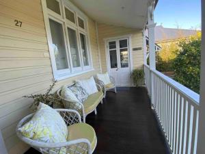 una veranda con tre sedie di vimini su una casa di Sylvester’s on Lamont. Arty in Invermay. a Invermay
