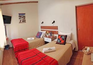 a hotel room with two beds and a red suitcase at La Fortaleza del Inca in Lunahuaná