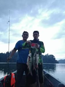 two men holding fish on a boat on the water at Royal Belum Mystical in Gerik