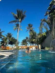 uma piscina com palmeiras e uma pessoa na água em Beira-mar Tamandaré / Carneiros em Tamandaré