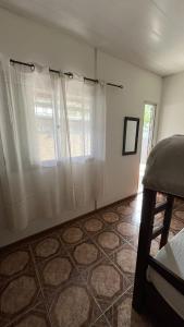 a bedroom with a window with white curtains at Casa cabaña in Paysandú