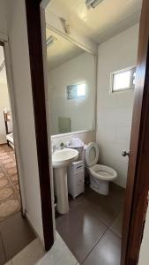 y baño con lavabo, aseo y espejo. en Casa cabaña, en Paysandú