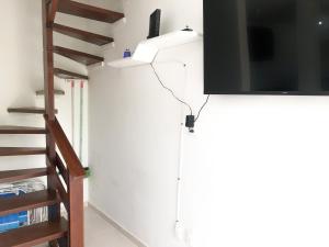 una TV appesa a un muro accanto a una scala di Apartamento de 3 quartos em Jurerê a Florianópolis