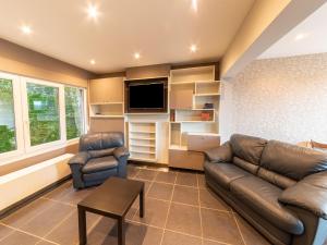 ein Wohnzimmer mit einem Sofa und einem TV in der Unterkunft Magnificent accommodation for 7 travellers with hot tubs in Esneux