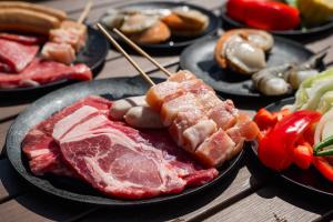 una mesa cubierta con platos de comida con carne y hortalizas en Yagaji Beach(屋我地ビーチ), en Nago